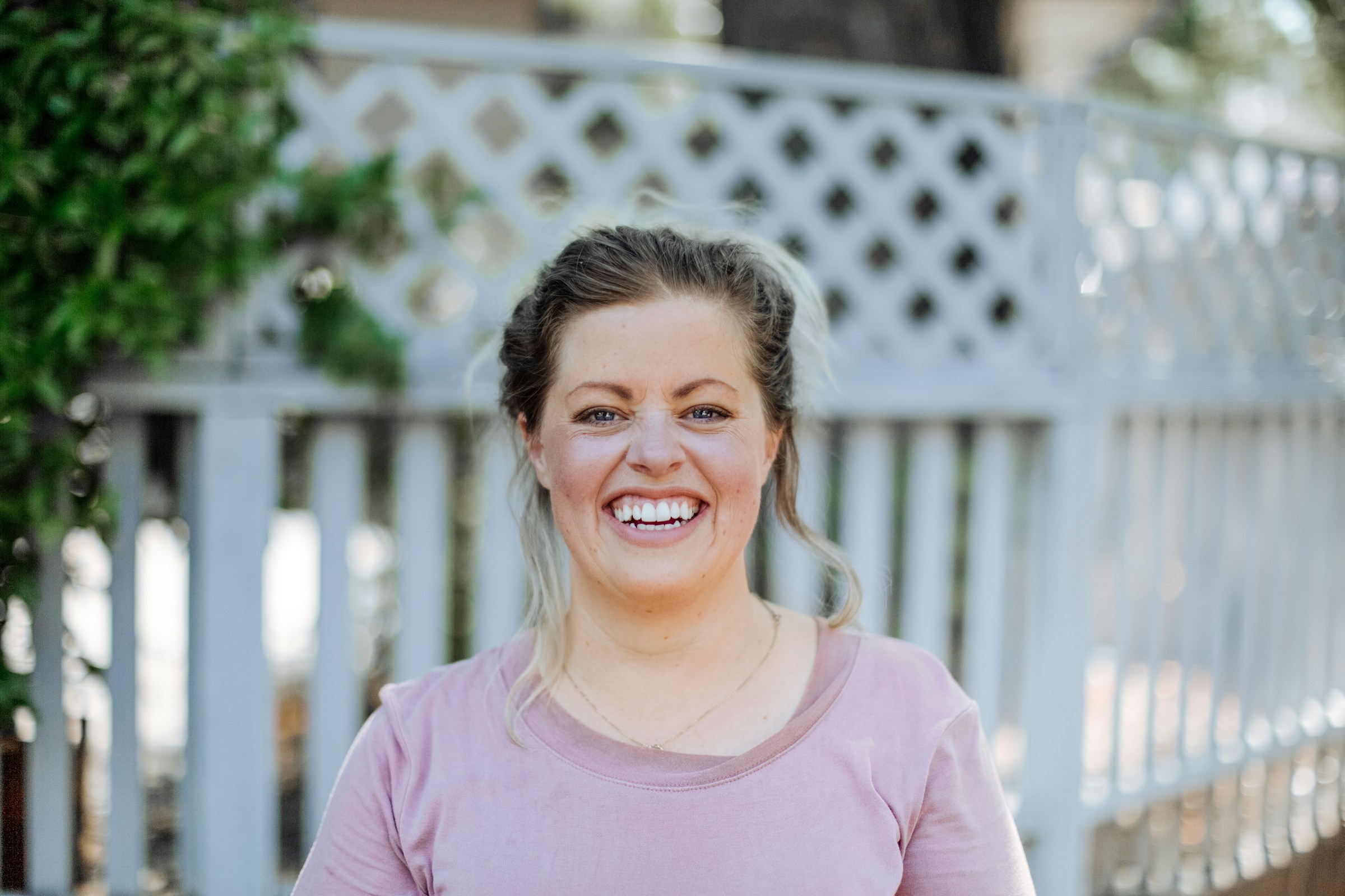 Smiling woman in front of a white fence