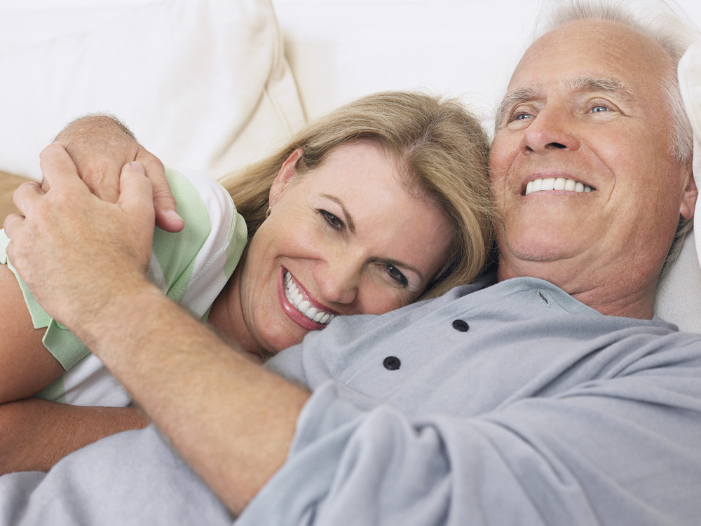 older couple lying down, cuddling and smiling