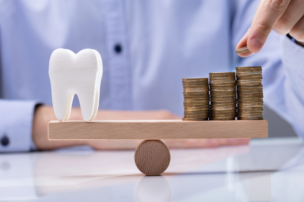 Man Placing Coin On Top Of The Stack Coins And Tooth Over Seesaw